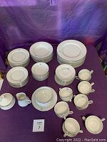 Full set of Mikasa fine china pieces arranged on purple cloth including plates, bowls, cups, creamer, sugar bowl.