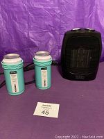 Photo showing Black and Decker ceramic space heater (black) with two turquoise Artican Corkcicle stainless steel cooling cans and a MaxSold lot number card.