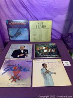 Photo of six vinyl record album covers arranged in two rows with purple background, featuring artists Henry Mancini, Johnny Mann Singers, Glenn Miller, and others.