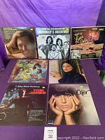 Seven vintage vinyl LP records with album covers shown on display against a purple backdrop. Visible artists include Tom Jones, Cher, Jackie Gleason, The 6th Dimension, and others.
