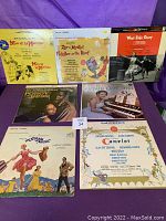 Front view of seven vintage vinyl record album covers from original Broadway shows and movies including Man of La Mancha, Fiddler on the Roof, West Side Story, Porgy and Bess, My Fair Lady, Gigi, The Sound of Music, and Camelot.