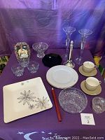 Photo shows assorted glassware and dinnerware including Eloquent Ink Nigella platinum square plate, small cut glass bowls, Two & One cups with saucers, crystal candle holders, and decorative vase.
