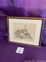 Full view of the framed architectural drawing of a house with a flag mounted on a purple backdrop.