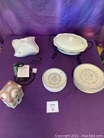 Full lot overview on purple draped table includes plates, Christmas bank, serving dishes, candle