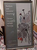 Full view of the framed poster showing the artwork and text, set on a floral patterned rug and leaning against a furniture piece.