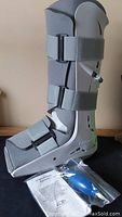 Full view of the Aircast FP Walker boot showing the gray Velcro straps, foam lining, and plastic frame, with inflation pump and instruction packet included.