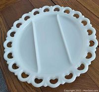Top view of the round milk glass tray showing open lace heart shaped edge and two divided compartments.