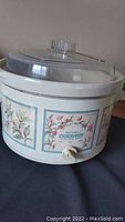 Full view of the Rival Crock Pot with floral design and clear lid with vent.