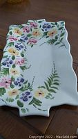 Top view of rectangular platter showing colorful hand-painted flowers in pink, purple, yellow, and green leaves with a wavy edge design.