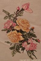 Close-up of the large floral cross stitch piece featuring yellow and pink roses on cream Aida cloth with visible weaving texture and stitching details.