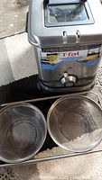 Photo showing T-fal deep fryer with control knob and two metal mesh sink strainers in front.
