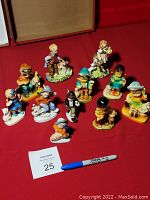 Photo showing 11 vintage hand-painted figurines of children with their pets arranged on a red surface.