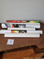 Rolled-up posters on a wooden surface showing size and quantity