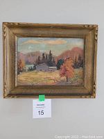 Close view of framed oil painting showing autumn landscape with house, trees, and signature.