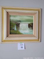 Framed oil painting showing waterfall and two figures with signature visible in corner