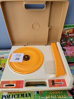 Front open view of the beige and yellow Fisher-Price record player with volume and speed controls showing the turntable and built-in speaker.