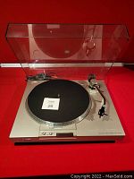Sony stereo turntable in working condition with clear plastic dust cover lifted open showing the turntable mat and tonearm.