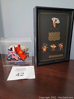 Clear acrylic block displaying a fragment of the original Berlin Wall with a color map of divided Berlin. The block sits next to a black framed display case containing 1988 Seoul Olympics pins.