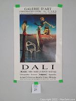 Front view of Salvador Dali exhibition poster displayed with painter's tape on corners, showing full image and text.