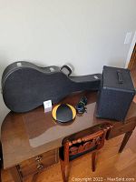 Overview showing guitar case, amplifier, stand pouch and cable on table