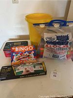 Display of all items in the lot including card holders, bingo game, Texas Hold'em set, large blocks, and yellow bucket.