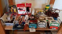 Full lot shown on wooden table including nails, tools, ropes, mouse traps, and paint supplies.