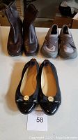 Top view showing all three pairs of shoes including brown leather boots, gray canvas athletic shoes, and black leather flats with Michael Kors logo