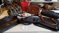Image showing six handbags of varying colors and materials arranged on a table including leather and fabric types.