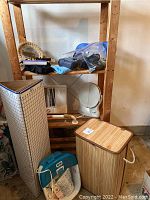 Photo showing bamboo hamper, Homedics foot bath, two makeup mirrors, and bag of hair accessories on wood shelving unit