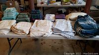 View of folded sheet sets and pillowcases on table, showing neutral and blue tones