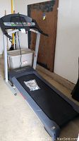 Full side view of the treadmill showing the running belt and frame in a garage setting.