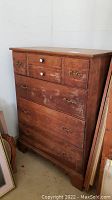 Front view of the wooden dresser showing all four drawers with mixed hardware and finish wear.