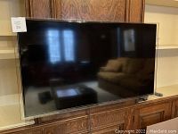 Front view of TV mounted on wood cabinet, reflecting room