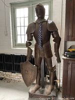 Front view of full suit of armour on wooden base holding shield