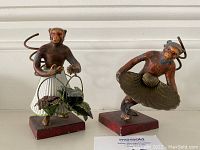 Front view of both monkey figurines on red painted wooden bases