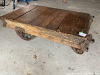 Side angle view showing full table structure, wooden top and cast iron wheels