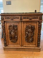 Front view of oak cabinet showing carved doors, drawer fronts and marble top