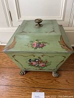 Full front view of green painted toleware coal bucket with floral decoration and claw feet