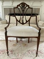 Full front view of the chair showing carved lyre back, arms, upholstered seat and tapered legs