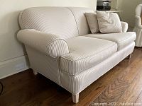 Three-quarter view of love seat showing fabric pattern and wooden legs