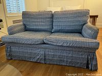 Front view of cotton plaid love seat showing two seat and back cushions, skirted base, and rolled arms.