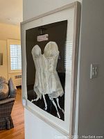 Side-angle view of framed painting mounted on wall showing frame depth and black background