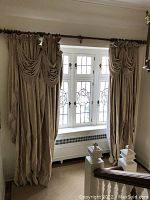 Full view of two damask curtain panels hanging on a rod in front of window