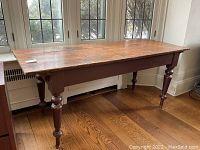 Full front view of the table against window, showing 3-board plank top and turned legs