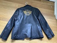 Back view of black leather jacket showing gold Ralph Lauren logo graphic