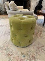 Green velvet pouf ottoman showing button tufting detail and overall shape.