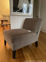 Front three-quarter view of the grey velvet lounge chair on hardwood floor