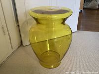 Front view of translucent yellow acrylic table showing vase-shaped base and round top
