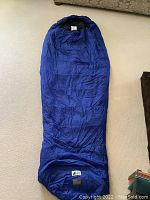 Full view of the blue sleeping bag laid out flat showing its mummy-style shape and closed foot section.