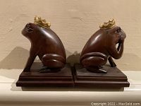 Front view of the pair of carved wooden frog bookends with crowns